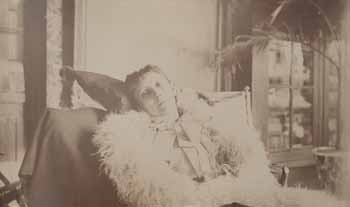 Emily Beale in hammock in glass room, wrapped in white fur Photograph